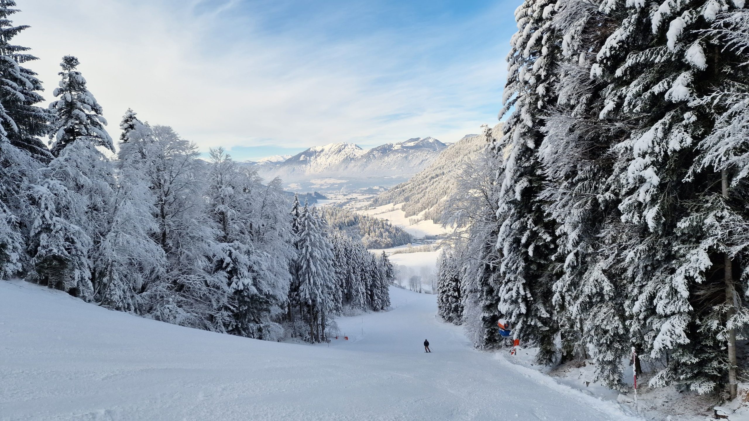 Besneeuwde skipiste met een skiër.